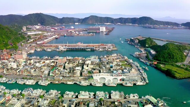 Aerial view of Suao Harbor with many docking boats and houses on island - Beautiful mountain scenery in background