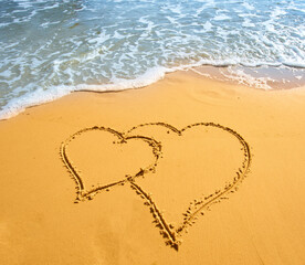 Two hearts handwritten on sand of tropical beach