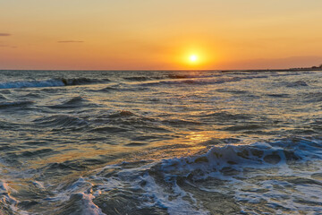 Soft sea waves and bubbles on the beach with sunset sky