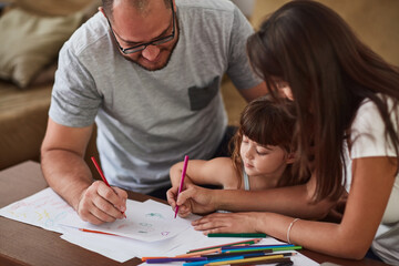 Fototapeta premium They encourage creative play in their home. Shot of a mother and father drawing together with their young daughter at home.