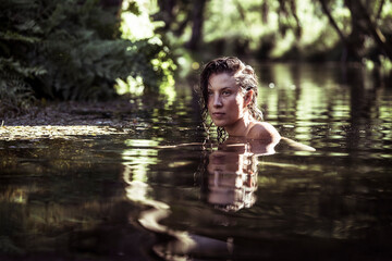 Portrait of beautiful young natural woman in green water river