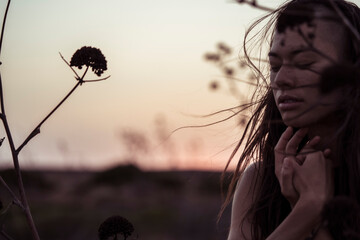 portrait of a dancer in the wind at dusk with coastal flowers