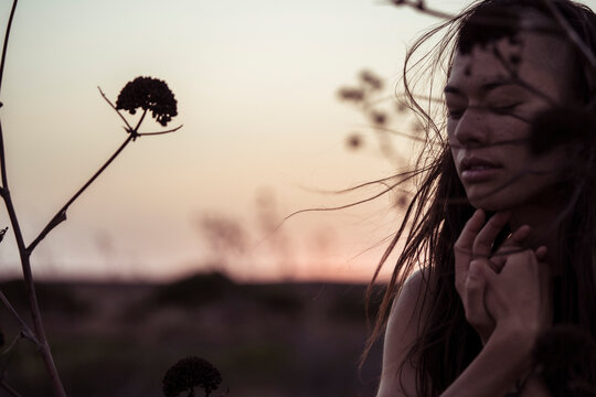 portrait of a dancer in the wind at dusk with coastal flowers
