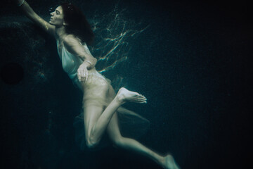 Woman dancer swimming up to emerge from deep water