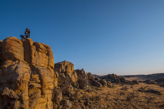 woman resting on top of cliffs in the Gobi desert