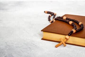 Old Bible book with wooden christian rosary beads