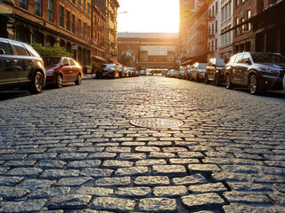 Old cobblestone street with cars parked along the curb in the Tribeca neighborhood of Manhattan in New York City - obrazy, fototapety, plakaty