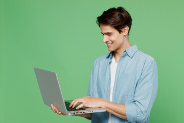 Fun cheerful happy blithesome young brunet man 20s years old wears blue shirt hold use work on...