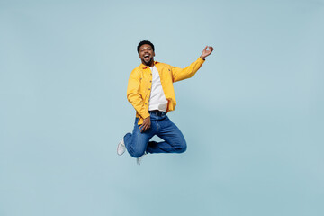 Fototapeta premium Full body expressive singer young man of African American ethnicity 20s in yellow shirt jump high play guitar isolated on plain pastel light blue background studio portrait. People lifestyle concept