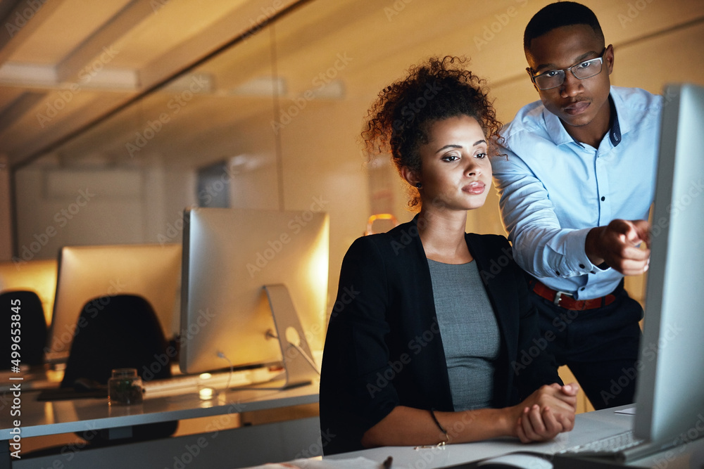 Poster let no minute go to waste. shot of two businesspeople working together on a computer in an office at