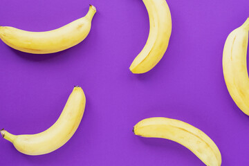 Ripe yellow bananas on purple background, texture