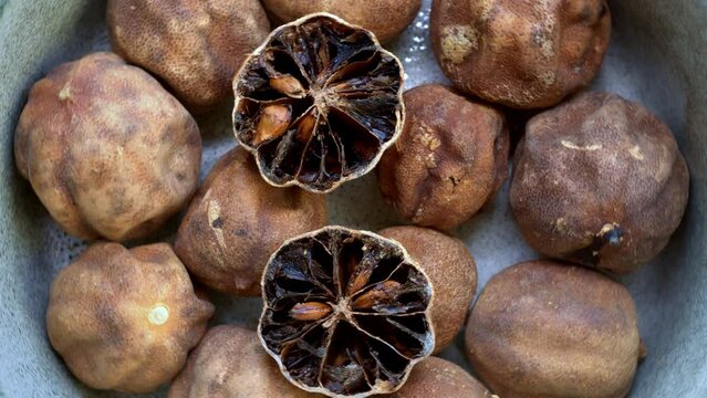 Persian dried whole limes (limu omani) in bowl. Top view, table spin.