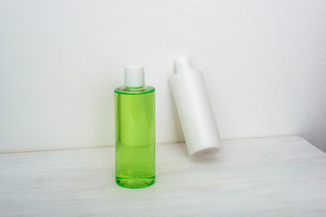 Green and white cosmetic bottles with shower gel and body lotion on white background. Natural organic cosmetics concept. Front view, mock up