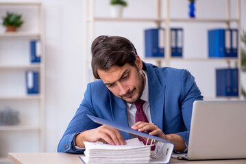 Young male employee and too much work in the office