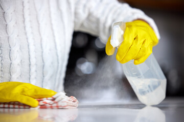 Always use a strong disinfectant. Shot of a woman spraying her kitchen counter to clean it.
