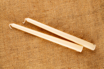 Two paraffin candles on jute fabric, close-up, top view.