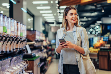 Beautiful woman grocery shopping with cellphone