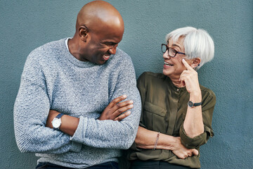 Its always good vibes when were together. Shot of two cheerful mature businesspeople having a discussion while standing against a wall outdoors.