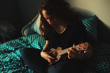 Mujer tocando ukulele en su habitación. Concepto de musica.