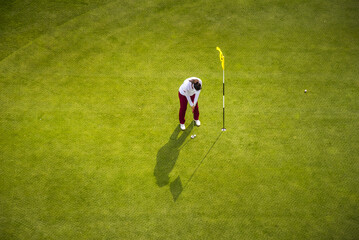 A young woman playing golf, photographed from above.