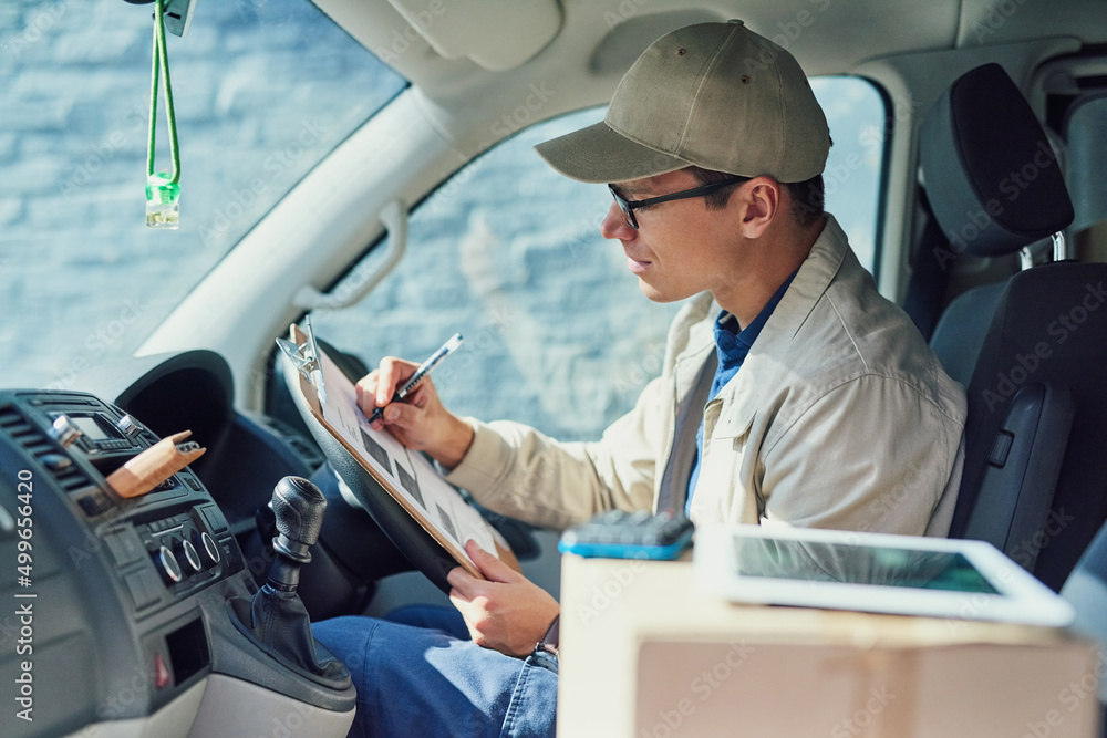 Poster well deliver to wherever you are. shot of a courier writing on a clipboard while sitting in a delive