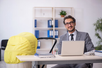 Young male employee looking after new born at workplace