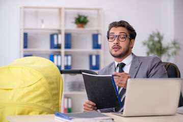 Young male employee looking after new born at workplace