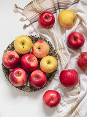 Wicker basket with fresh red and yellow apples on a kitchen table. Top view. Healty eating and vegan concept.
