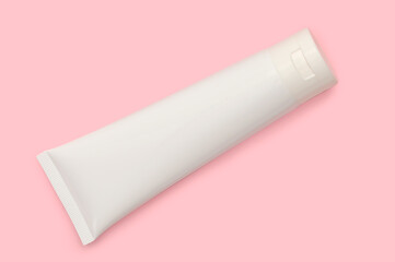 White cosmetic bottle on a pink background. Cream for body care.