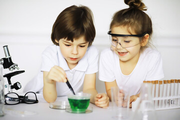Obraz na płótnie Canvas Two cute children at chemistry lesson making experiments on white background