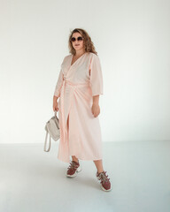 teen leisure. young plus size girl with red hair is standing in pink summer dress with white...