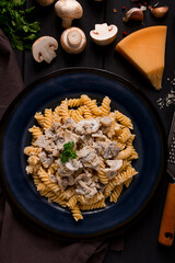 Fusilli pasta, with champignons in cream sauce, top view, with ingredients, on a wooden table, no people,