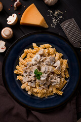 Fusilli pasta, with champignons in cream sauce, top view, with ingredients, on a wooden table, no people,