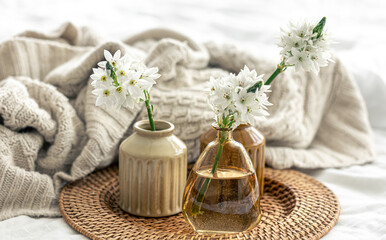 Home composition with flowers in vases and a knitted element.