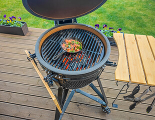 Large kamado type barbeque grill with roasted fresh vegetables on a cast iron