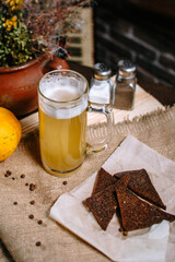 Beer in a large mug, standing on the table. Fried toast from black bread in a plate.