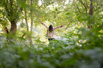 Obraz premium woman with open arms wearing a raincoat in the forest