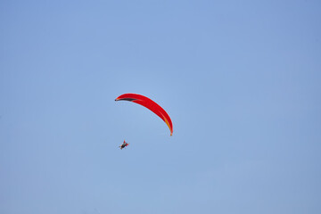 Paragliding in the sky. Paraglider flying in bright sunny day. Beautiful paraglider in flight on a turquise background.