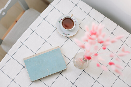 modern interior design of a cozy living room with dry plants in vase, book and tea cup on the table 