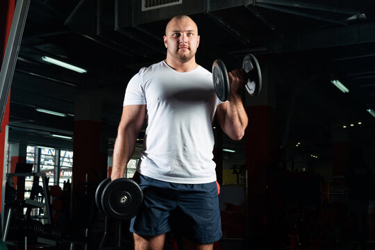 Male bodybuilder engaged with dumbbells in the gym