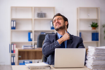 Obraz premium Young male employee and too much work in the office