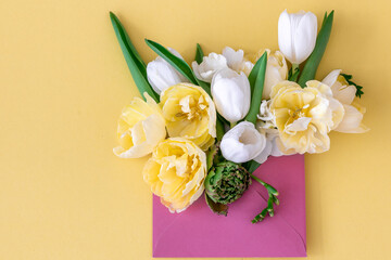 Flowers in an envelope on a colored background, flat lay.