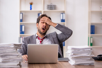 Young male employee unhappy with excessive work in the office