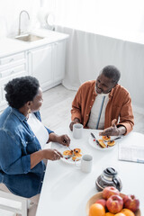 high angle view of senior african american man talking with wife during breakfast.