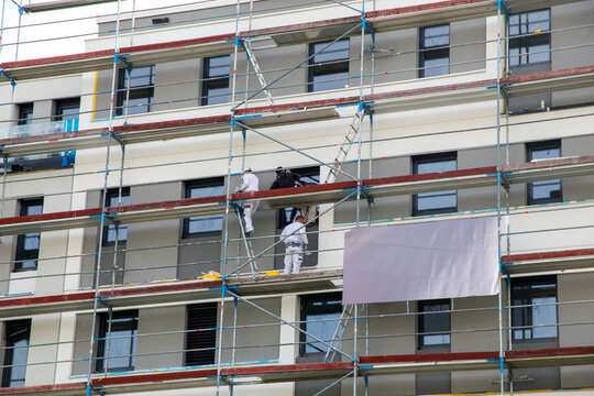 Maler beim Fassadenanstrich eines neuen Apartmentgebäudes