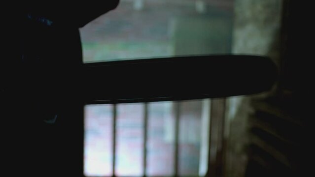 Silhouette of man holding chainsaw inside dark smoked place . Scary man with chain saw in horror halloween scene . Friday 13th theme . Close up . Slow Motion