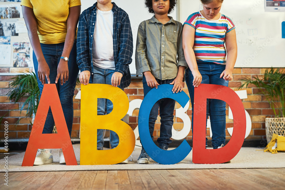 Poster Working on our language skills. Cropped shot of a diverse group of children standing and holding the alphabet letters in their classroom at school.