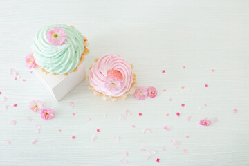pink and green cupcakes with spring flowers  on wooden podiums on white  background