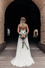 concept and stylish bride holding a beautiful wedding bouquet behind her back