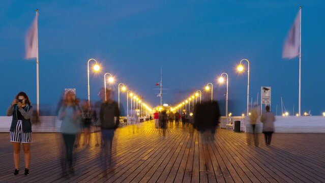 Sopot, Poland. An evening time-lapse of a long wooden pier in Sopot, Poland, with a view of blurred people and a blue sky, zoom in